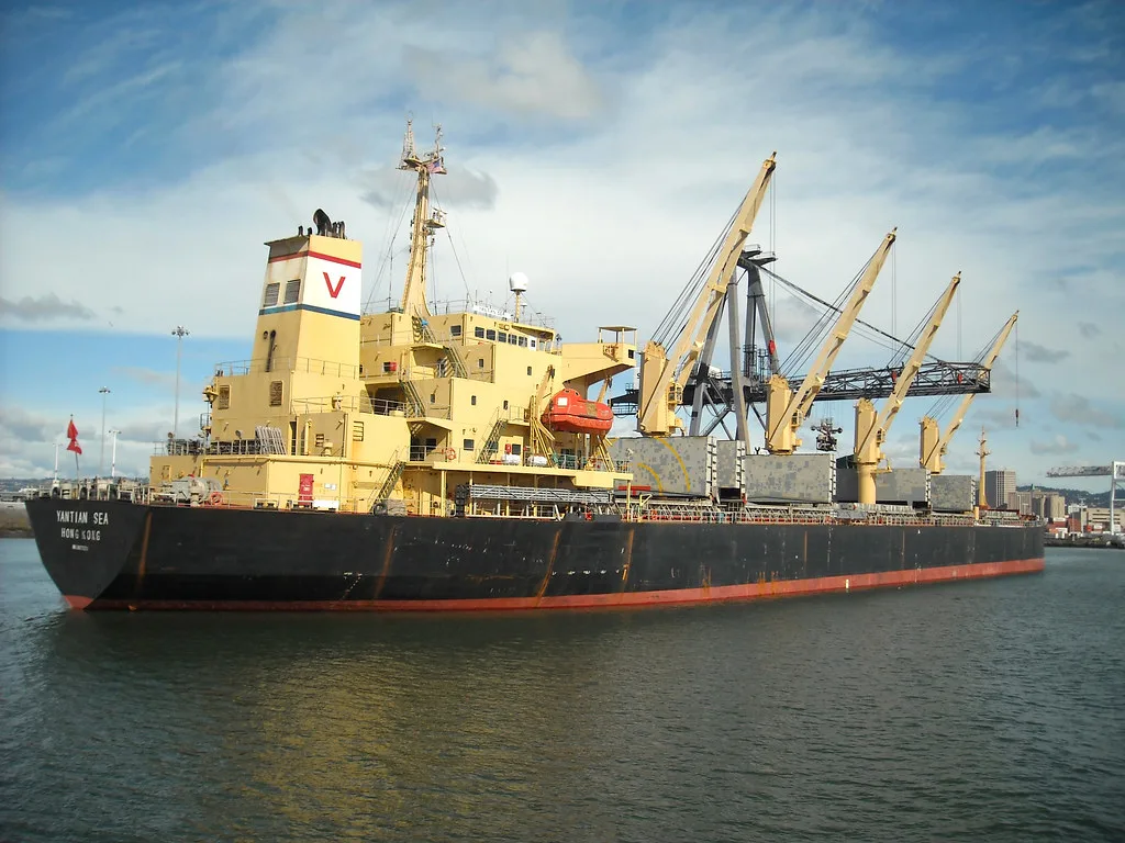 A general cargo ship alongside with its derricks rigged