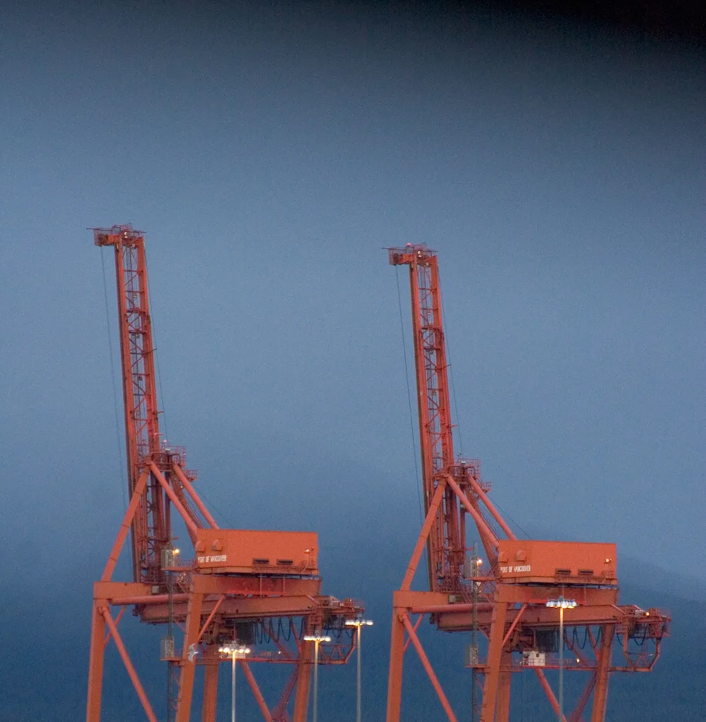 Two container cranes silhouetted over a berth