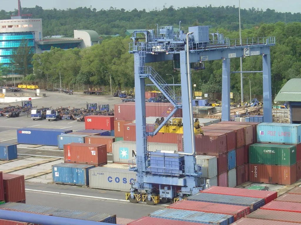 A straddle carrier moving containers across a terminal yard